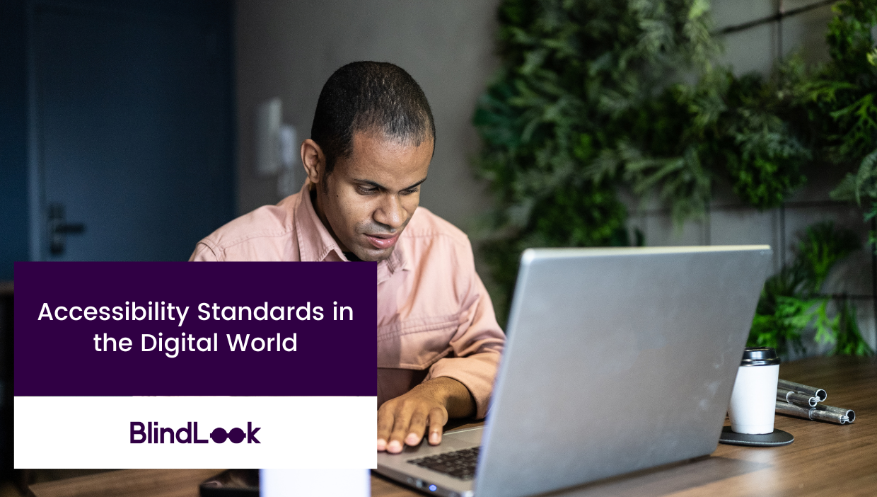 A visually impaired man is seated at a desk, using a laptop. He appears focused, and the setting includes a background of greenery on the wall. A white coffee cup and some office supplies are on the wooden desk. The text overlay reads, "Accessibility Standards in the Digital World" with the BlindLook logo below it.